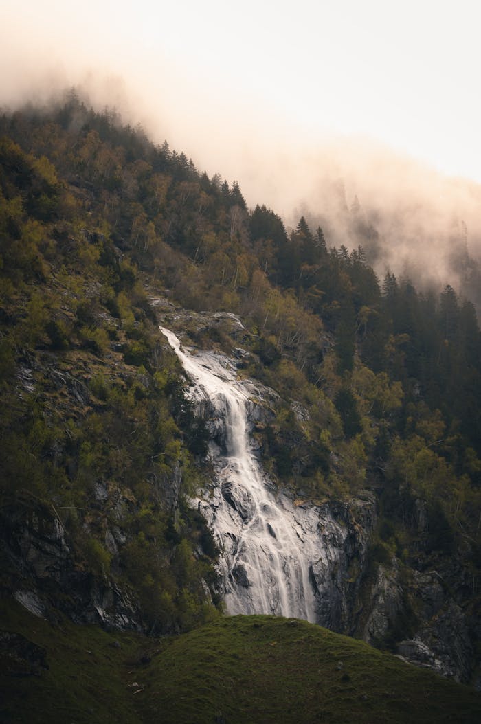 A beautiful waterfall flows down a mist-covered mountain in Ginzling, Tirol, Austria.