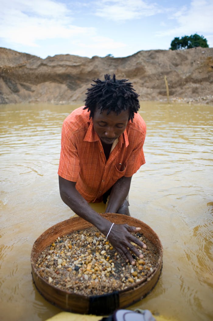 A man processes gravel in search of diamonds in a water-filled pit, Sierra Leone.